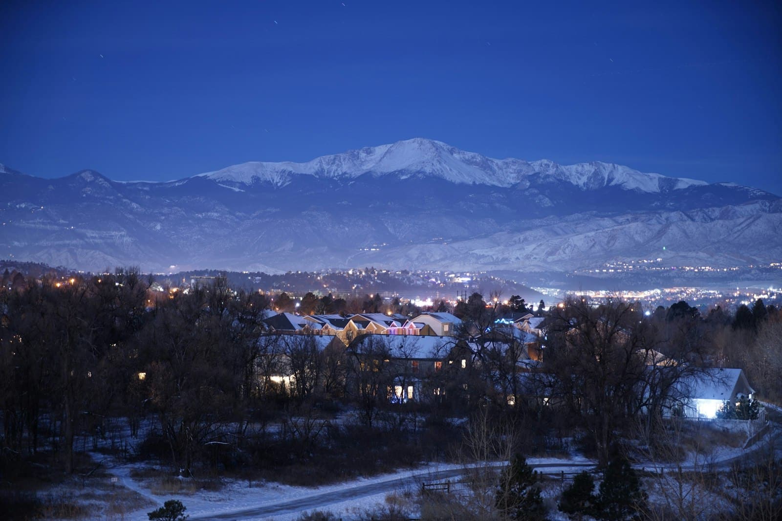 Colorado Springs homes under a snow-covered Pikes Peak on a winter evening